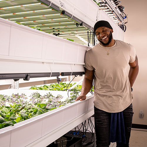 A person standing next to plants growing indoors.